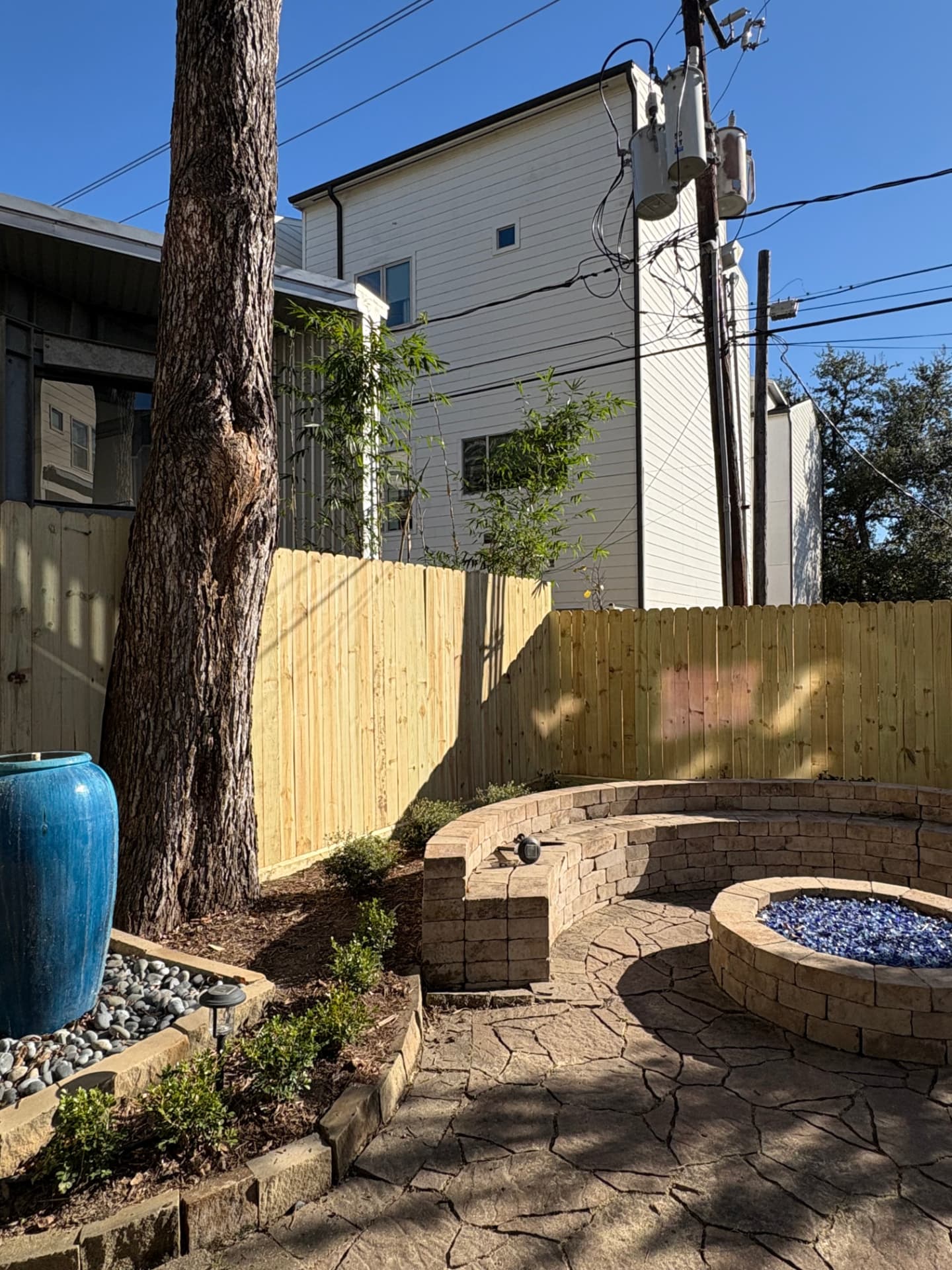 Wood privacy fence enclosing a courtyard with a seating wall and fire pit in the Heights, Houston, TX