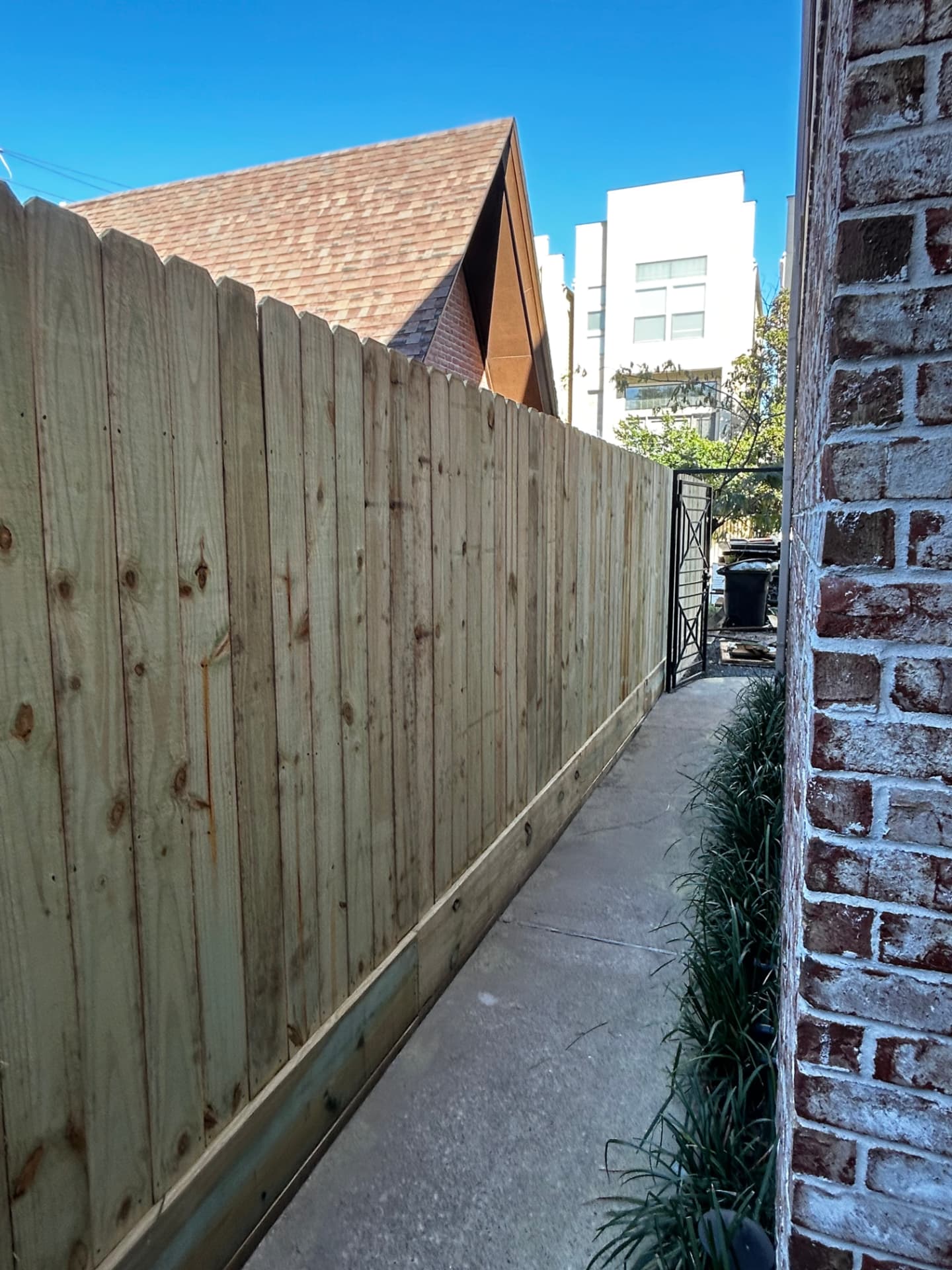 Wood privacy fence with rot board along a narrow side yard walkway in the Heights, Houston, TX