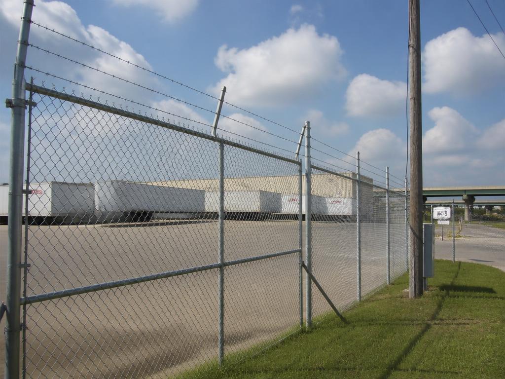 Commercial chain link security fence with barbed wire installed around a warehouse in Houston, TX