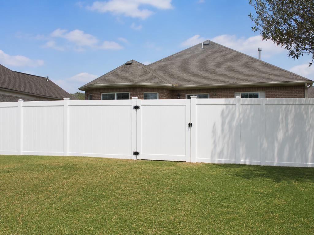 White vinyl picket fence and matching gate in the front yard of a home in Richmond, TX
