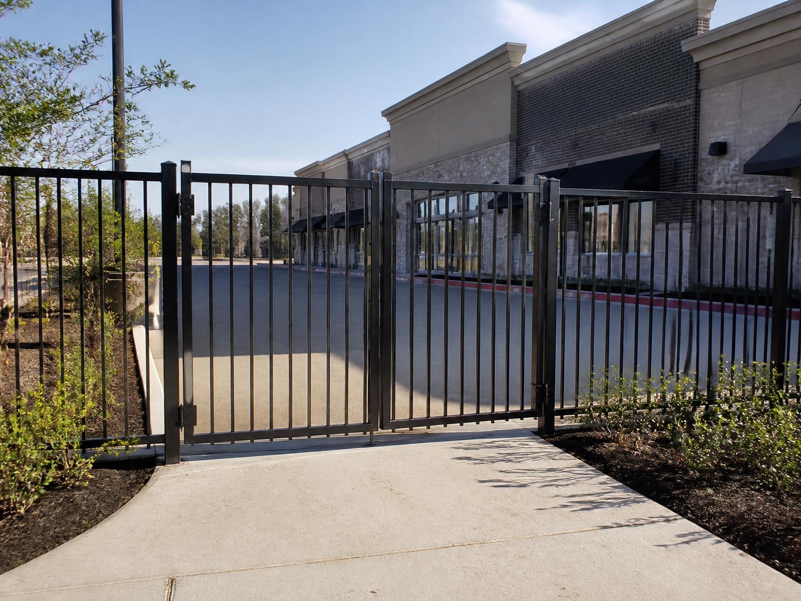 Black powder-coated aluminum commercial fence and double swing gate at a retail center in Spring, TX