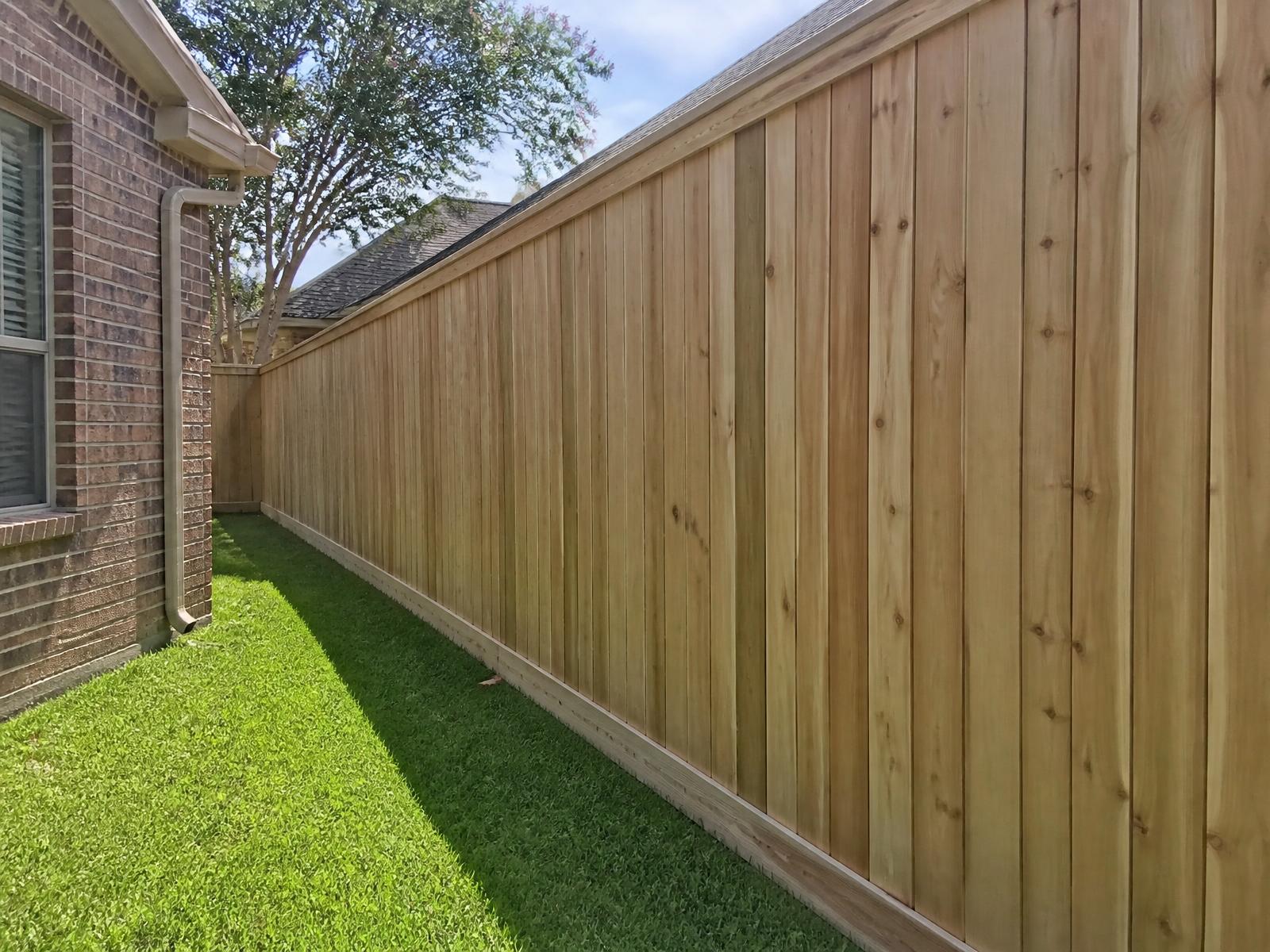 Cedar board-on-board privacy fence with rot board along the side yard of a brick home in Sugar Land, TX